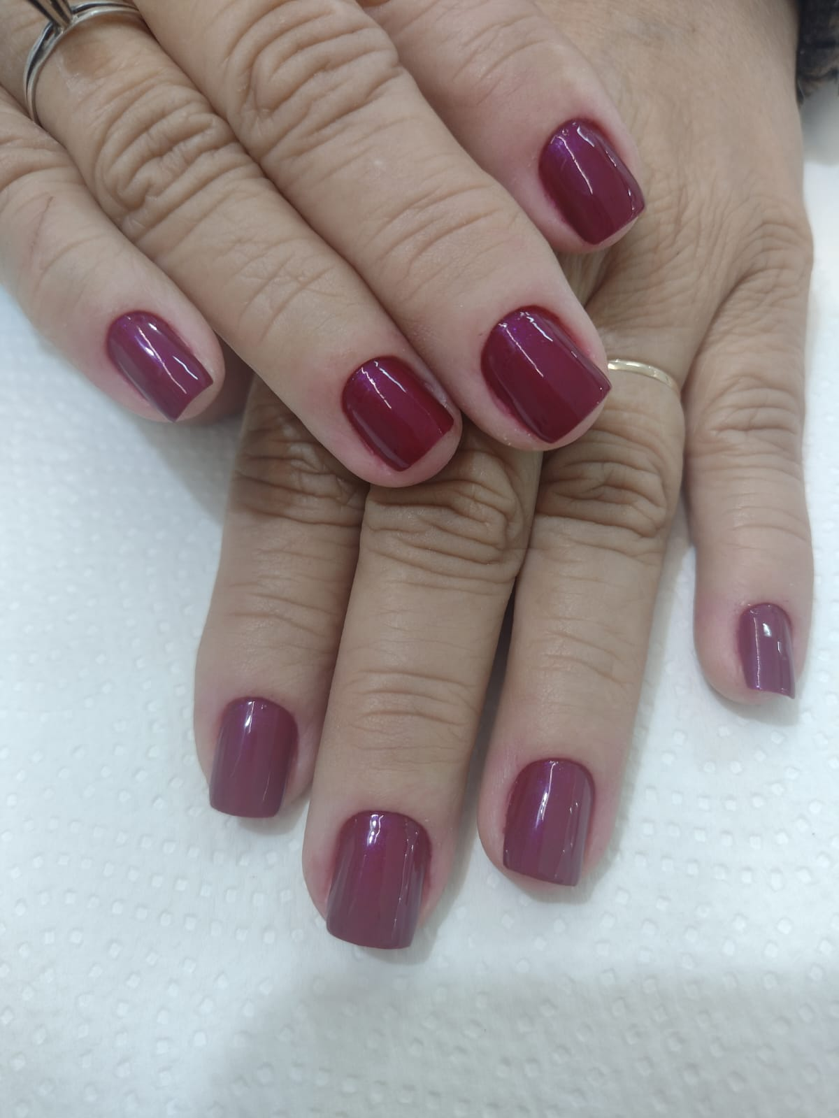 Unhas quadradas com esmaltação vinho brilhante feita em manicure tradicional em Alvorada RS